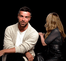 a man in a white sweater is sitting next to a woman in a black dress