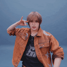 a man wearing a brown jacket and a black shirt with the letter h on it is dancing