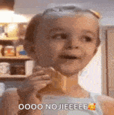 a little girl is eating an ice cream cone in a kitchen .