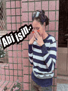 a woman in a blue and white striped sweater covering her face with her hands with the words abi isin above her