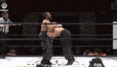 two men are wrestling in a wrestling ring with a referee watching .