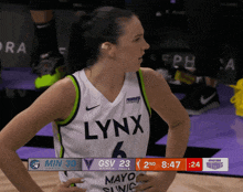 a woman wearing a lynx jersey looks at the scoreboard