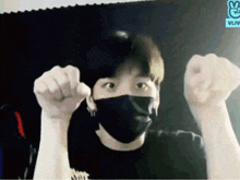 a man wearing a black mask is making a funny face with his hands in the air .