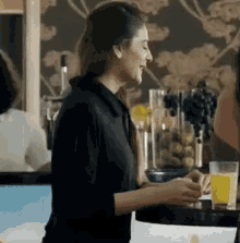 a woman in a black shirt is sitting at a table with a glass of orange juice .