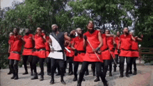 a group of men wearing red shirts and black pants are dancing