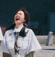 a woman wearing a white shirt and tie laughs with her mouth open