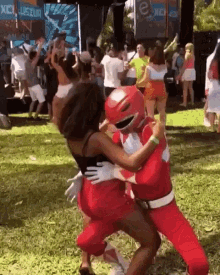 a man in a red power ranger costume is hugging a woman in the grass