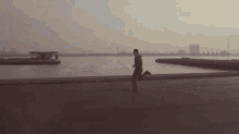 a man is running on a sidewalk near the water .