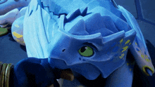 a blue dragon with green eyes is laying on the ground