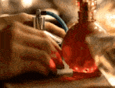 a person spraying perfume on a red bottle with a blue hose