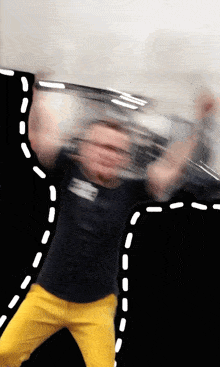 a blurry picture of a man wearing a black shirt with the letter e on it and yellow pants