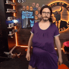 a man in a purple dress is in front of a sign that says son of the fee