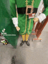 a mannequin dressed in a green elf costume has a sign that says 1011 140 032