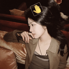 a woman sitting on a couch with a hand sticker on her head