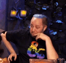 a man with blue hair is wearing a black t-shirt with a dragon on it