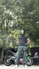 a man wearing a helmet stands in front of a motorcycle with a tiktok watermark on the bottom