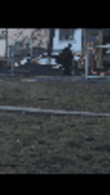 a blurry picture of a park with a fence and a few buildings in the background
