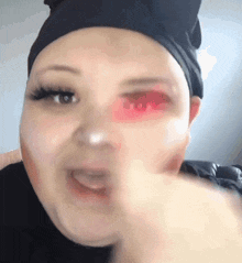a woman wearing a black headband has a red eye