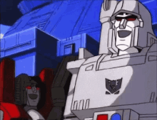 a couple of transformers are standing next to each other in front of a blue building .