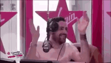 a man wearing headphones is sitting in front of a microphone with his hands in the air .