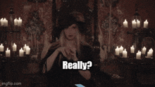 a woman in a black hat is sitting in a chair and says how 'd you learn so much about science ?