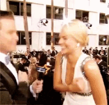 a woman in a white dress is talking to a man in a suit
