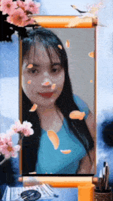 a woman in a blue shirt is surrounded by pink flowers and petals