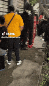 a group of people are standing on a sidewalk with a tik tok watermark