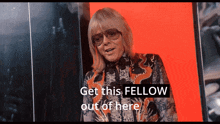 a woman wearing sunglasses and a floral shirt says " get this fellow out of here "