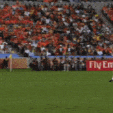 a soccer player runs with a ball in front of a kia motors sign