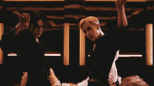two men are dancing in a dark room with their arms in the air