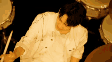 a man in a white shirt is playing drums and the word lje is on the screen