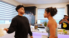 a man and a woman are standing next to each other in a kitchen with a man wearing a shirt that says hot honey