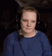 a woman wearing headphones and a blue sweater is sitting in a chair .