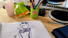 a drawing of a cat is on a desk with a samsung monitor