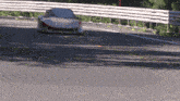 a car driving down a road with a white fence in the background