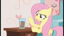 fluttershy from my little pony is sitting at a table with a glass of chocolate milk .
