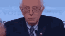 a close up of a man wearing glasses and a suit giving a speech .
