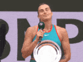 a woman holding a trophy and a microphone in front of a bnp sign