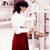 a woman in a red skirt is standing next to a shelf