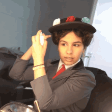 a woman wearing a hat with flowers on it is applying makeup