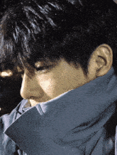 a close up of a person 's face with a blue jacket covering their neck