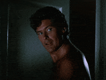 a shirtless man stands in front of a white door