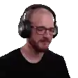 a man wearing headphones and glasses is standing in front of a white background .