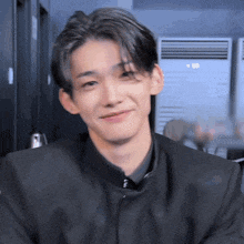 a young man wearing a black jacket and a black shirt is smiling