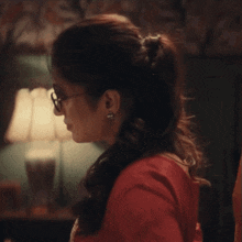 a woman wearing sunglasses and a red shirt is looking down