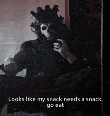 a man in a skull mask is sitting in a chair with the words looks like my snack needs a snack go eat