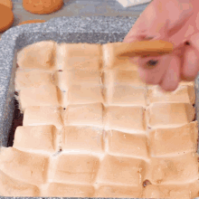 a person is dipping a cookie into a casserole dish filled with marshmallows