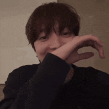 a person covering their mouth with their hand in a dark room