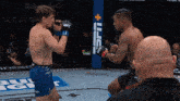 two men are fighting in a ufc ring with a ufc banner in the background